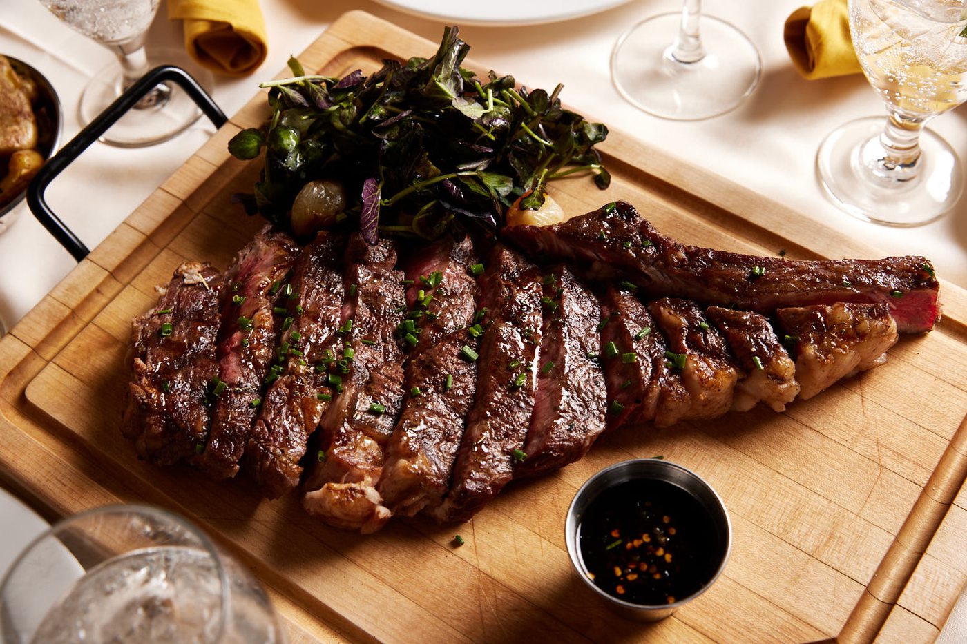 A sliced tomahawk steak on a carving board at Shallots Bistro
